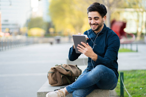 Young man having a video call on digital tablet outdoors. - Zdjęcie, obraz