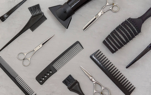 Cadre complet avec outils de coiffure, peignes, ciseaux sur fond gris. Accessoires de salon de coiffure, vue de dessus. - Photo, image