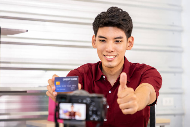 Joven hombre asiático bloguero comerciante en línea utilizando la cámara de vídeo en vivo para vender, con tarjeta de crédito. Redes sociales, Influencer, compras en línea y concepto de pago. - Foto, Imagen