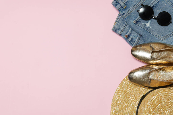 Semplice outfit estivo su sfondo rosa con spazio copia, camicia, blue jeans, cappello di paglia, occhiali da sole neri e sneakers bianche. Oggetti alla moda delle donne, vista dall'alto. - Foto, immagini