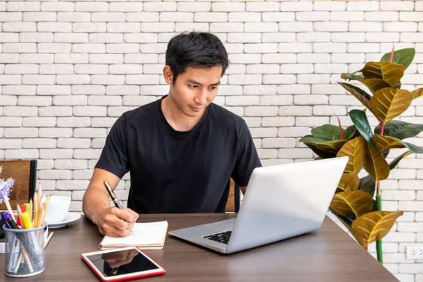 Portrait of Asian man freelancer working at home, sitting at desk dining table in living room - Photo, Image