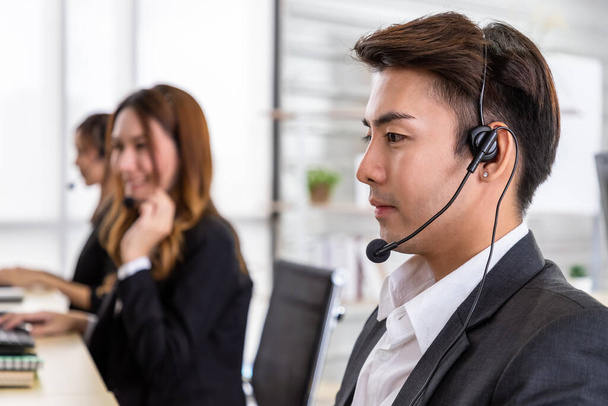 Jeune asiatique mâle service à la clientèle agent opérateur équipe travaillant dans le bureau du centre d'appels avec écouteurs et ordinateur. - Photo, image