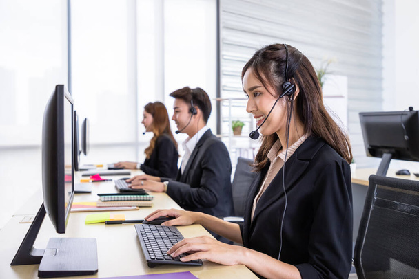 Young Asian female customer service support agent operator team working in call center office with headsets and computer. - 写真・画像