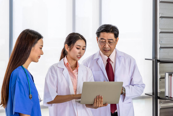 Happy Asian male and female medical doctor team standing and meeting discussion about vaccine with laptop computer - Photo, Image