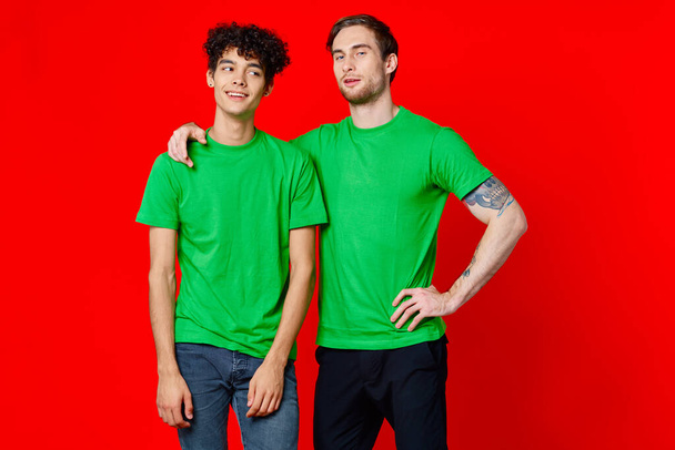 Yeşil tişörtlü iki adam yan yana duruyor. İletişim izole edildi. - Fotoğraf, Görsel