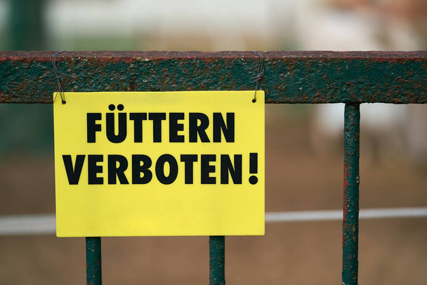    Sign with the inscription Feeding Prohibited (Fuettern verboten) on the fence to a riding club in Herrenkrug near Magdeburg in Germany                             - Photo, Image