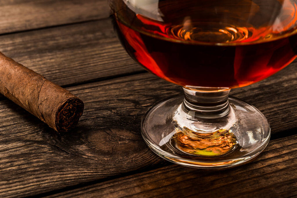 Glass of brandy and cuban cigar on an old wooden table.  - Fotoğraf, Görsel