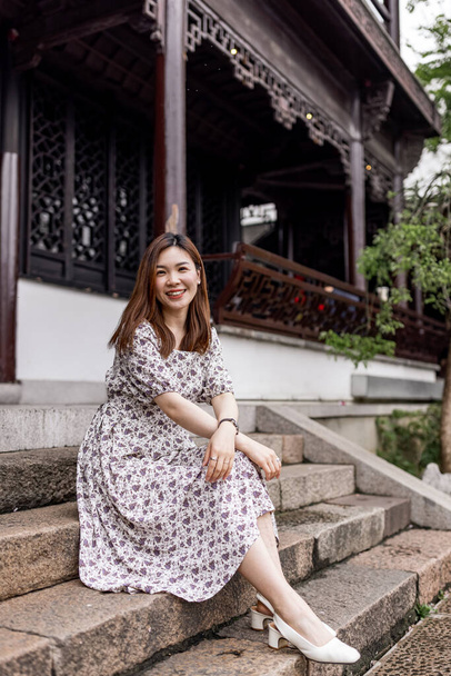 Portrait of young asian woman wearing stylish summer dress and walking outdoor in old city. Happy stylish woman with smiley face enjoys life - Photo, image