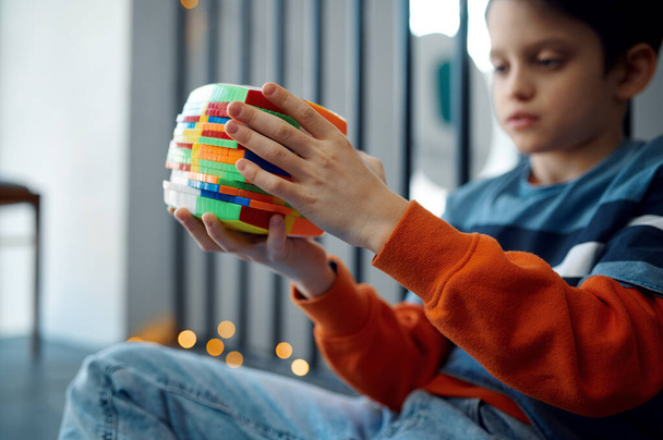 Kind versucht, schwierige Puzzlewürfel zu lösen. Spielzeug für Gehirn- und Logiktraining, kreatives Spiel, Lösung komplexer Probleme - Foto, Bild
