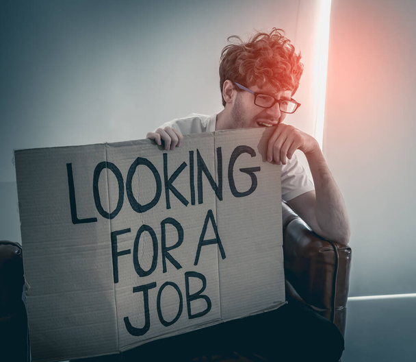 失業問題の概念のための仕事の段ボールを探している落ち込んでいる失業者の男. - 写真・画像