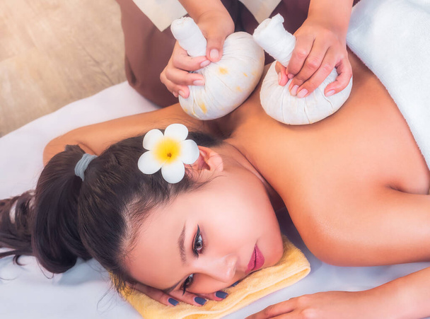 Jovem mulher asiática está tomando Thai Herbal bola massagem compressa quente em um autêntico spa - Foto, Imagem