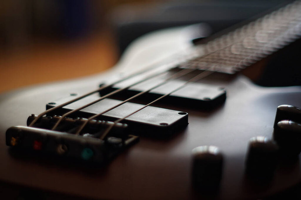 Closeup shot of a smooth body, pickups, bridge, knobs and strings of a bass guitar musical instrument with backlight - Photo, Image