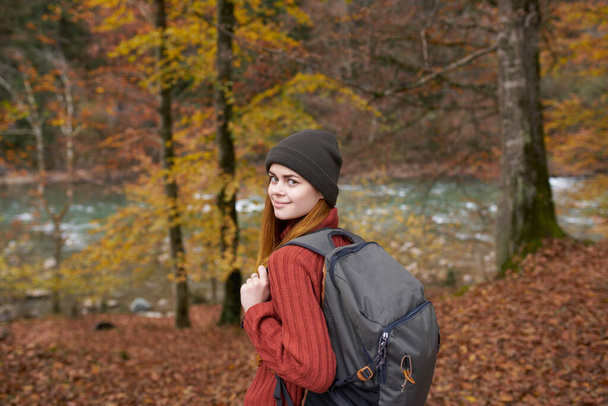 秋の森の自然景観背の高い木やバックパックを持つ女性ハイカー - 写真・画像