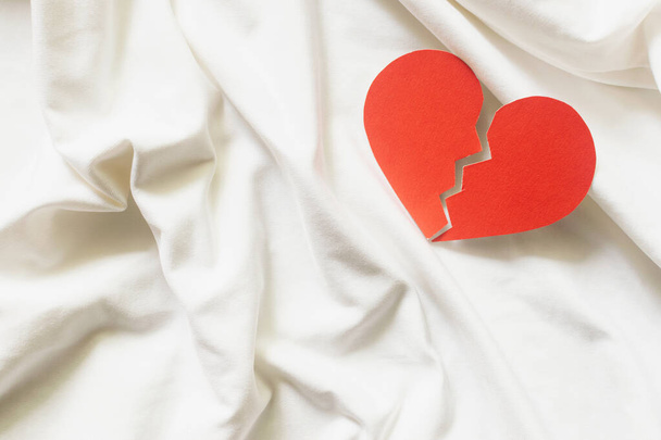 Corazón rojo roto en textil blanco. concepto de divorcio. - Foto, imagen