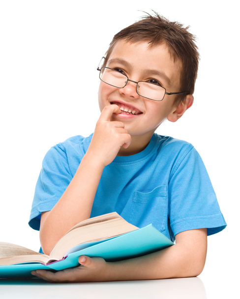 若い男の子は本を読みながら空想します。 - 写真・画像