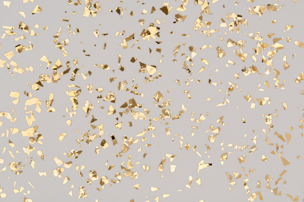Золотые конфетти на сером фоне, блестки из фольги для вечеринки. - Фото, изображение