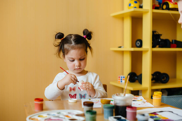 A cute little girl is playing and painting in her room. Recreation and entertainment - Zdjęcie, obraz