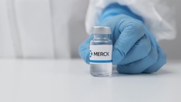 Merck vial with medicine put on the table by health worker in rubber gloves and PPE suit, May 2021, San Francisco, USA - Imágenes, Vídeo