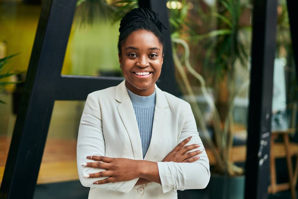 Νεαρή Αφροαμερικανή επιχειρηματίας χαμογελά ευτυχισμένη με σταυρωμένα τα χέρια στην πόλη. - Φωτογραφία, εικόνα