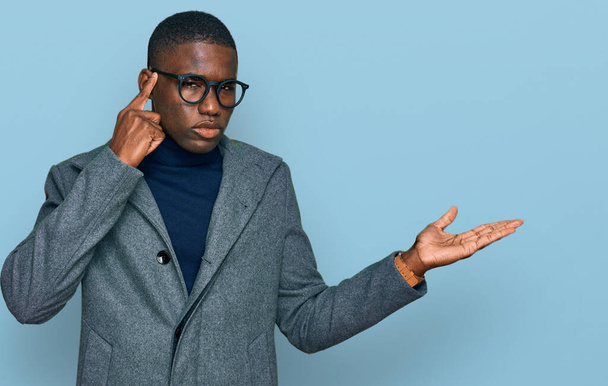 Giovane uomo afroamericano che indossa abiti da lavoro e occhiali confuso e infastidito con palmo aperto mostrando spazio copia e puntando il dito sulla fronte. Pensaci..  - Foto, immagini