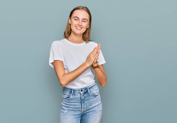 Beautiful young blonde woman wearing casual white t shirt clapping and applauding happy and joyful, smiling proud hands together  - Photo, Image