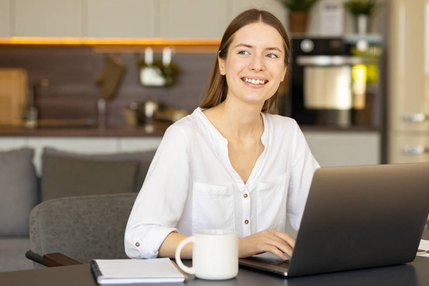 Happy caucasian woman freelancer sitting at her desk at home office and smiling. Successful young woman, real estate agent, satisfied with a good deal - Foto, Imagem