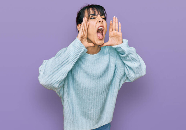 Giovane donna ispanica indossa vestiti casual urlando arrabbiato ad alta voce con le mani sulla bocca  - Foto, immagini