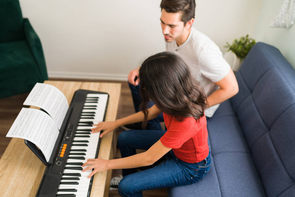 Tu t'en sors si bien. Jeune fille hispanique jouant une belle nouvelle chanson sur le piano avec son professeur de musique masculine   - Photo, image