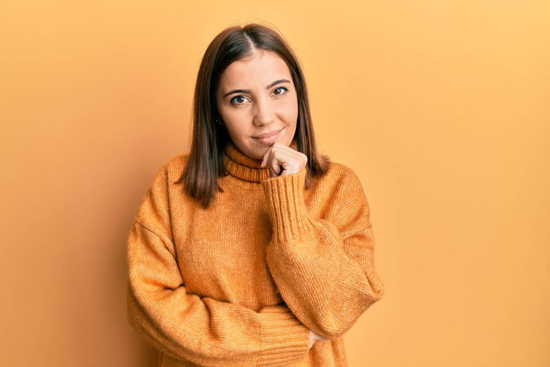 Young beautiful woman wearing turtleneck sweater smiling looking confident at the camera with crossed arms and hand on chin. thinking positive.  - Foto, Imagen