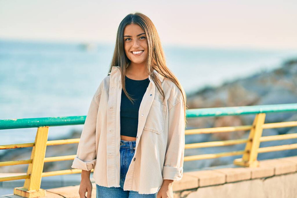 Young hispanic girl smiling happy standing at the promenade. - Фото, изображение