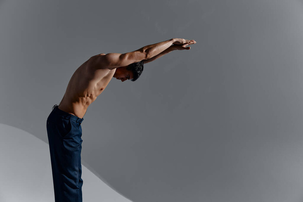 fisiculturista Homem de fitness com um torso bombeado e com braços levantados inclinados para a frente vista lateral - Foto, Imagem