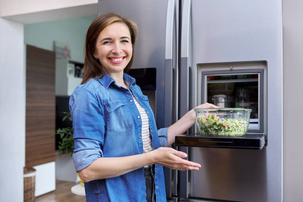 Woman with bowl of vegetable salad from refrigerator. - Foto, Bild