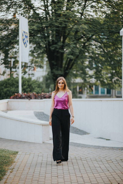 A gorgeous Caucasian female in stylish purple and black outfit posing in the park - Foto, afbeelding