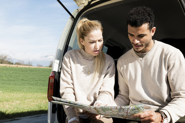 A young couple using a map on a road trip for directions - 写真・画像