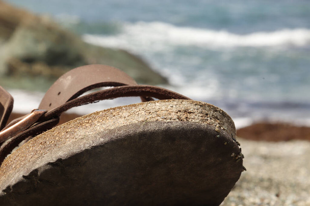Sandale sitzt auf dem Sand eines Strandes in der Nähe der Wasserlinie und Welle - Foto, Bild