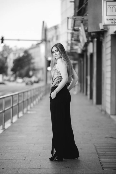 A grayscale of a gorgeous Caucasian female in stylish outfit posing in the street - Фото, зображення