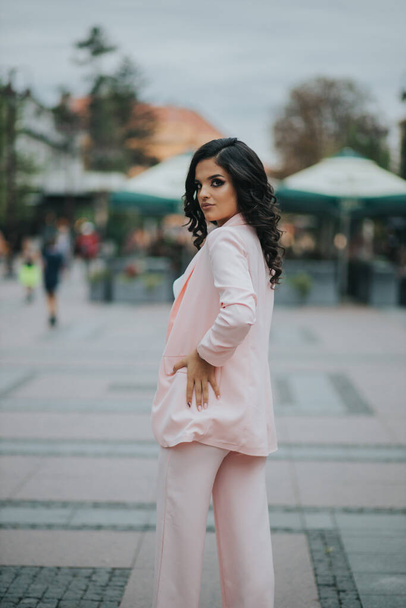 A gorgeous female in an elegant pink and white outfit on background of an urban park - Foto, Imagem