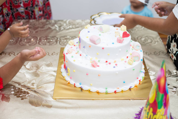 A closeup shot of hands cutting a colorful birthday cake and putting on a plate - Foto, Imagen