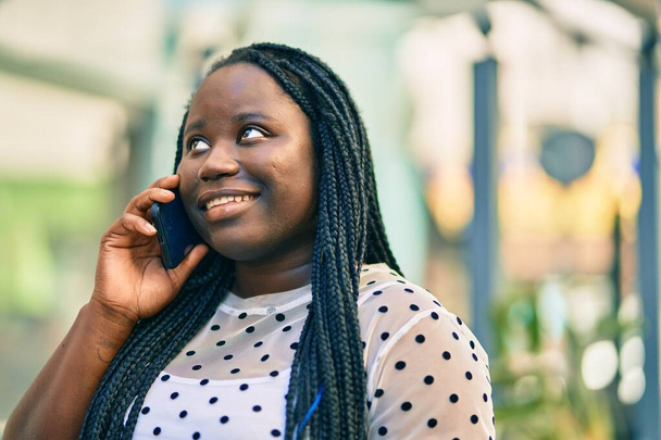 Giovane donna afroamericana sorridente felice parlando sullo smartphone in città. - Foto, immagini