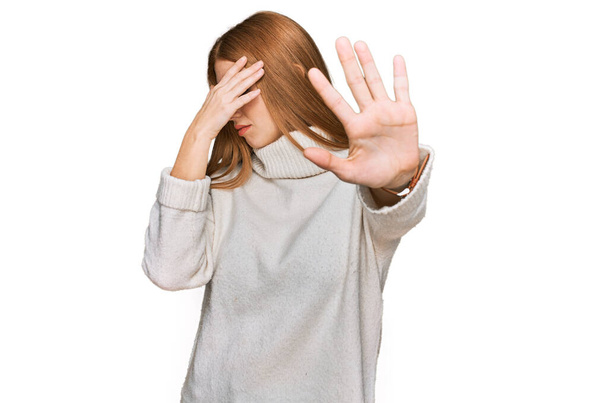 Mujer joven irlandesa que usa suéter de invierno casual cubriendo los ojos con las manos y haciendo gesto de parada con expresión triste y de miedo. concepto avergonzado y negativo.  - Foto, imagen