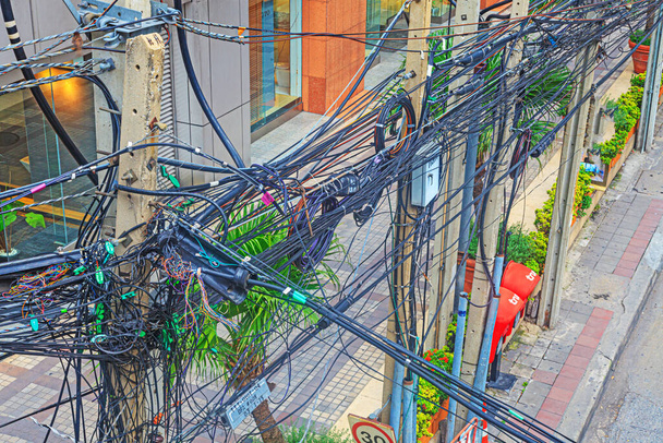 Chaotische Kabelverlegung von Strom- und Telefonkabeln auf einer Hauptstraße in Bangkok tagsüber - Foto, Bild