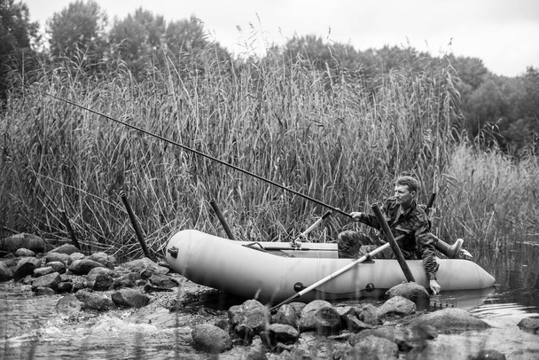 View of a fisherman rod fish on the river on a rubber boat. Black and white photo. - Photo, Image