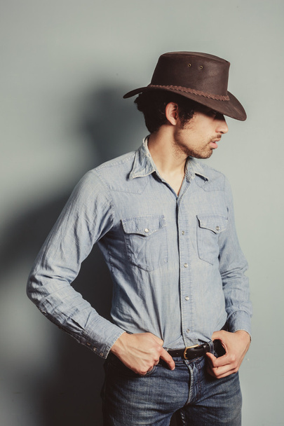 Cowboy standing by a blue wall - Фото, зображення