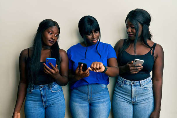 Троє молодих афроамериканських друзів, використовуючи смартфон, перевіряють час на наручних годинниках, спокійно і впевнено
  - Фото, зображення