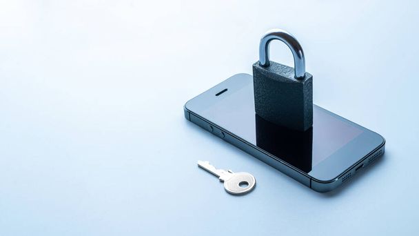 Liiketoiminnan turvallisuus. Moderni tilaa harmaa matkapuhelin riippulukko, avain valkoisella taustalla. Älypuhelin petos, online huijaus ja kyberturvallisuus uhka. - Valokuva, kuva