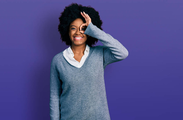 Молодая африканская американка в деловой одежде делает хорошо жест с улыбкой на руке, глаза смотрят сквозь пальцы с счастливым лицом.  - Фото, изображение