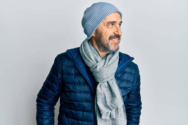 Uomo ispanico di mezza età che indossa lo stile invernale cercando di lato, posa profilo relax con viso naturale e sorriso fiducioso.  - Foto, immagini