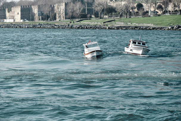 Turkije: 03.03.2021. Kleine vissersboot in bosporus istanbul tijdens zonnige dag vroeg in de ochtend met turquoise kleur marmara zeewater - Foto, afbeelding