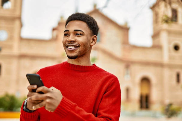 Bonito homem afro-americano ao ar livre usando smartphone digitando uma mensagem - Foto, Imagem