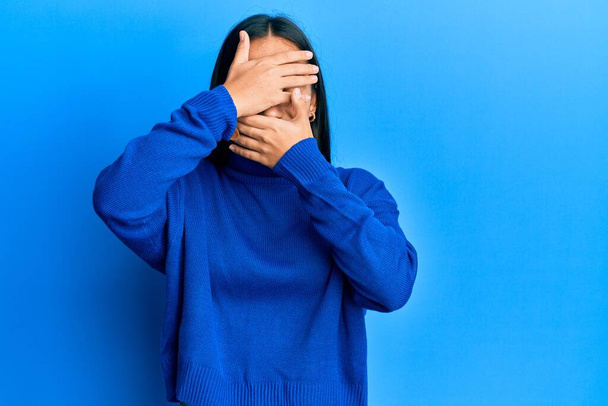 Молода азіатка в повсякденному зимовому светрі закриває очі і рот руками, здивована і шокована. приховування емоцій
  - Фото, зображення